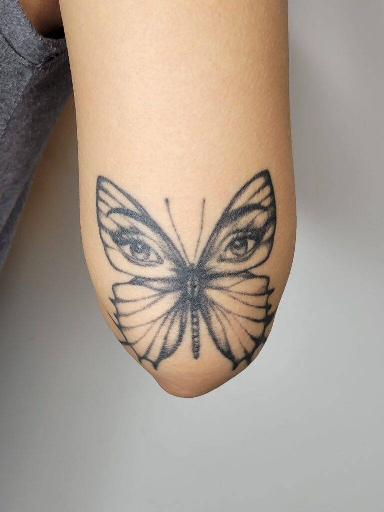 butterfly tattoo design of a butterfly with eyes on a females back arm above the elbow
