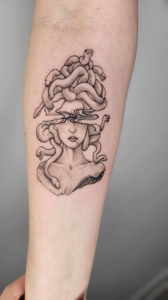 custom design of medusa in black and grey shading on a greek herma statue on a females forearm