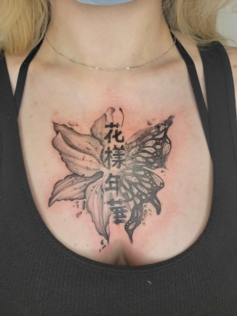 birth tattoo flower and butterfly with Japanese script on a chest of a female